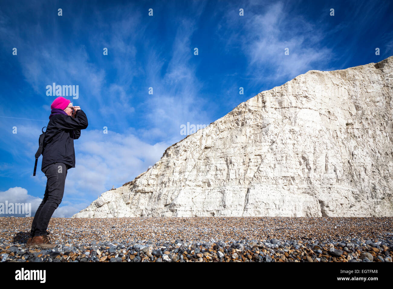 Auf einer sonnigen kalten Wintertag mit blauen Himmel im Hintergrund, eine Frau nimmt ein Foto der ersten der sieben Schwestern Kreidefelsen. Stockfoto