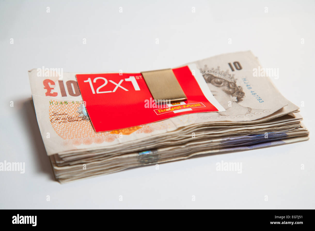 Ein Haufen von verwendeten UK Sterling Cash £20 und £10 Notizen mit einem Buch der ersten UK 1. Klasse Briefmarken Stockfoto