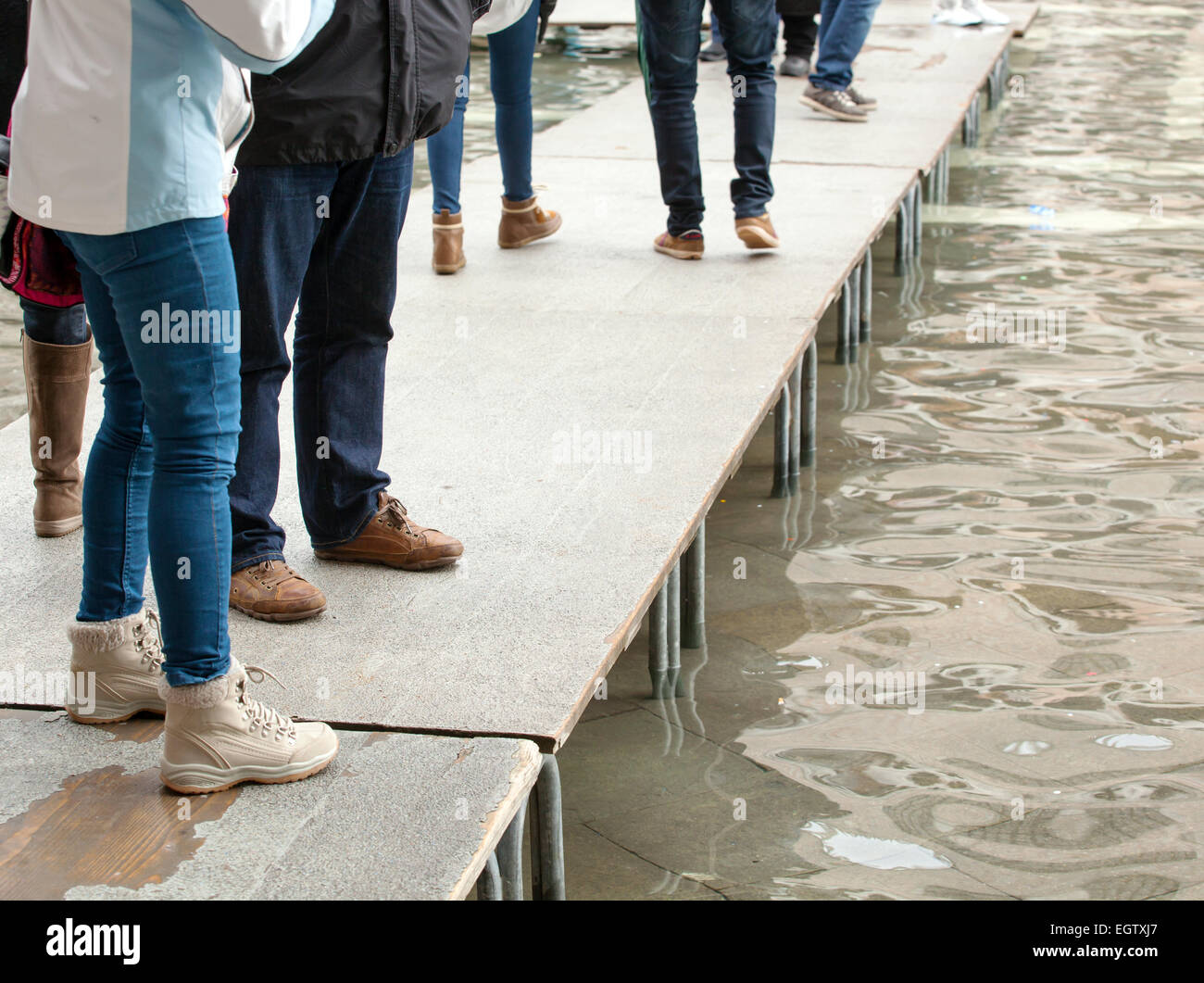 Menschen zu Fuß auf Laufsteg in Venedig während der Flut. Stockfoto