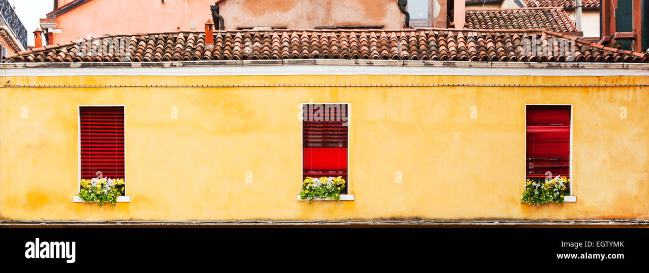 Drei rote Fenster mit Blumen eines typisch italienischen Hauses. Venedig, Italien. Stockfoto