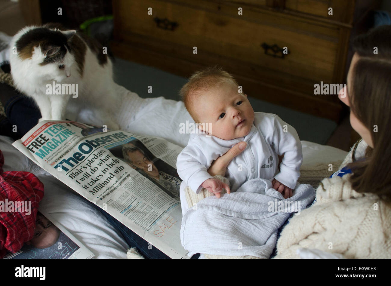 Ein sieben Wochen alten Baby junge Sonntagmorgen mit seiner Mutter und seiner Katze genießen. Stockfoto