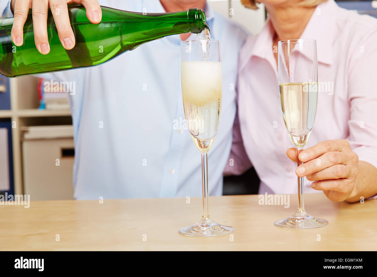 Altes Ehepaar Gießen Champagner im Glas für Silvester Stockfoto