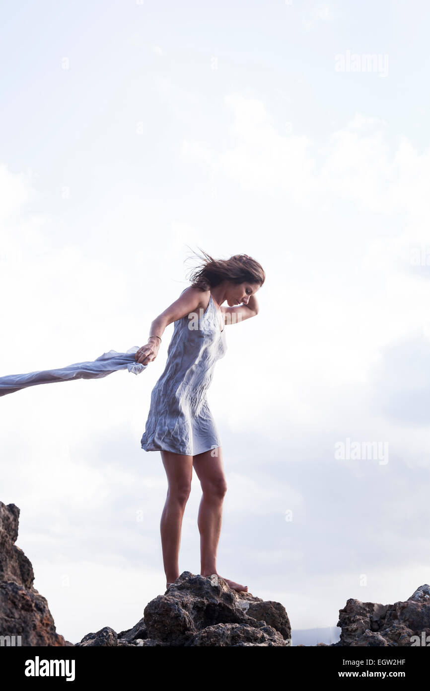 Frau stehend auf Felsen in der Nähe von Meer, Stoff im Wind zu halten. Stockfoto