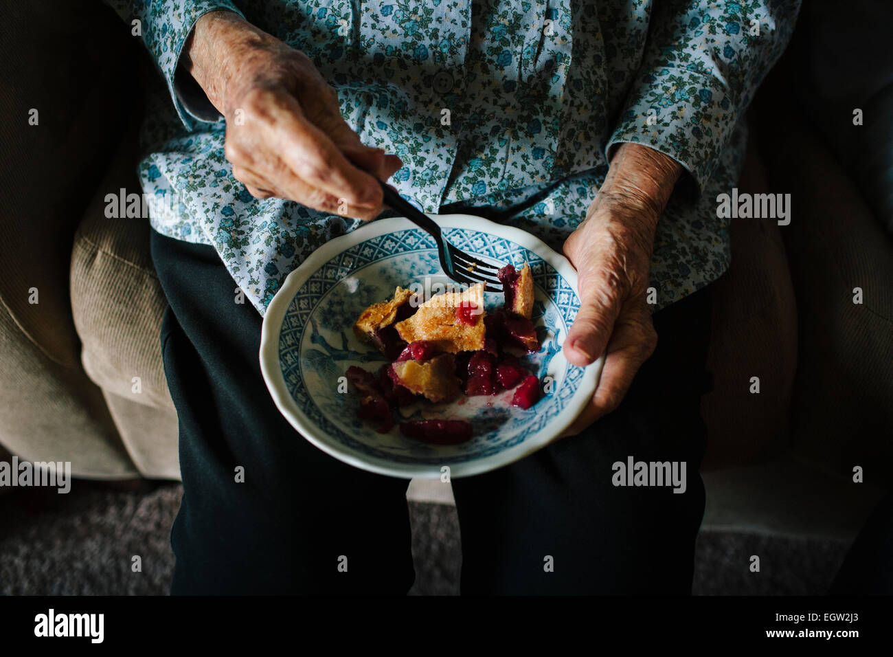 Ältere Frau essen eine Schale mit Kuchen. Stockfoto