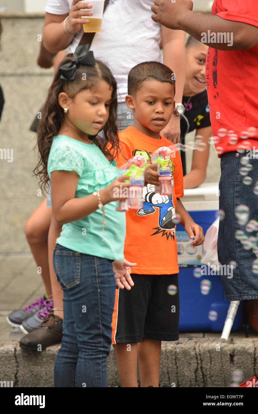 Puerto-Ricanischer Kinder spielen mit einem Blase Maschine Spielzeug auf der Straße eine Weile wartet der Karnevalsumzug in Ponce, Puerto Rico. Stockfoto