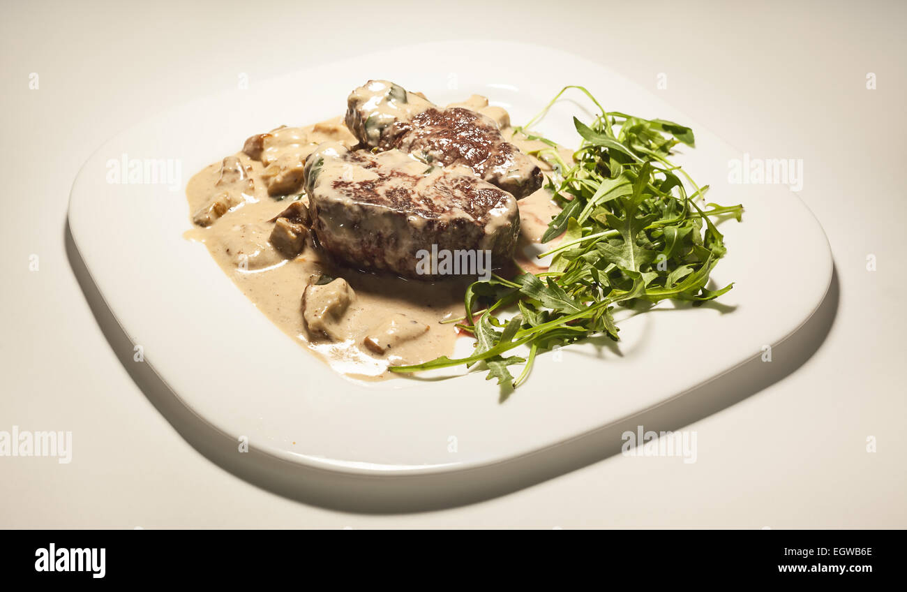 Steak in Sahne und Pilzen, serviert auf weißen Teller. Stockfoto