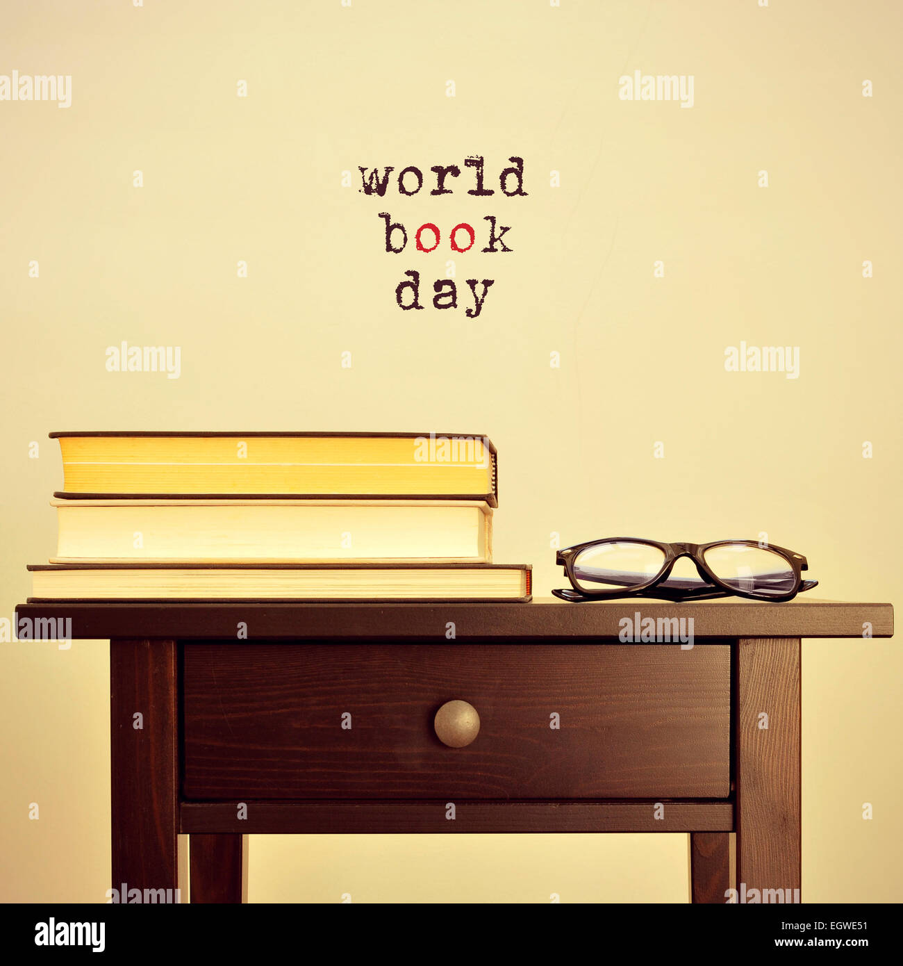 schwarze Brillen und einige Bücher auf dem Tisch und der Satz Welttag des Buches auf einem beigen Hintergrund, mit einem Retro-Effekt Stockfoto