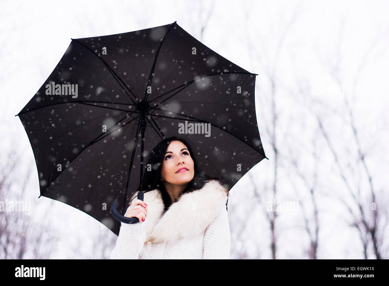 Frau mit Regenschirm zu posieren und das Nachschlagen während schneit Stockfoto