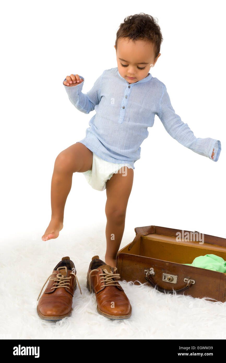 Spielerische afrikanischen Kleinkind Jungen Spaß mit Papas Schuhe Stockfoto