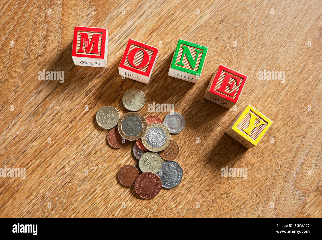 Holzziegel schließen Bausteine, die das Wort „Geld“ und „englische Münzen“ für das Geschäftskonzept „Cash Finance“ beschreiben Stockfoto