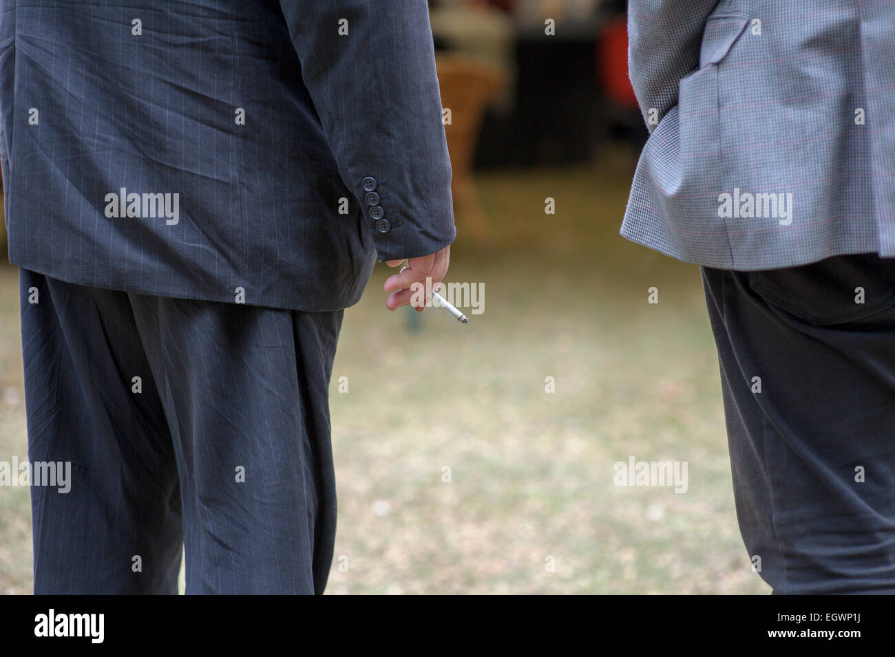 Eine Hüfthöhe Schuss von zwei Männern sprechen, hält man eine Zigarette in der rechten Hand. Stockfoto