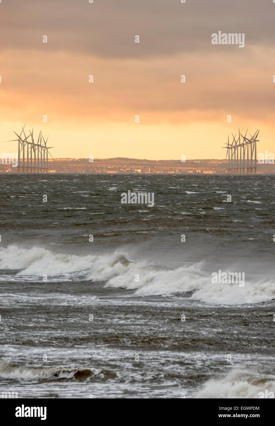 Sonnenuntergang über den Windpark Saltburn-by-the-Sea, Redcar und Cleveland, mit Wellen und Gischt an einem kalten Wintertag. Stockfoto