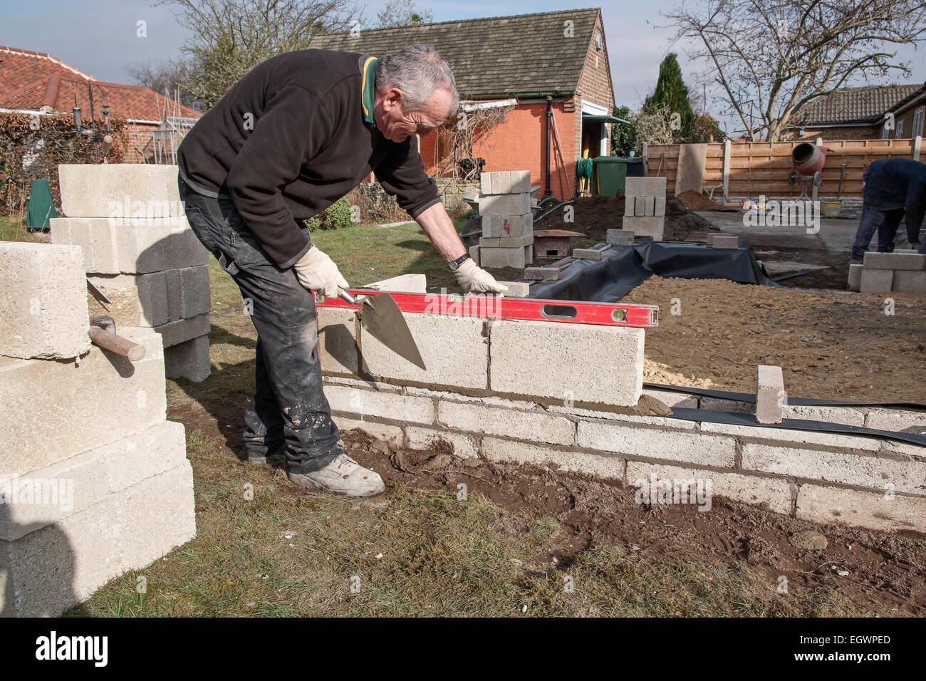 Bau einer Breezeblock Betonklotz Mauer Maurer prüft mit einer Wasserwaage auf eine britische home Improvement Projekt. Stockfoto