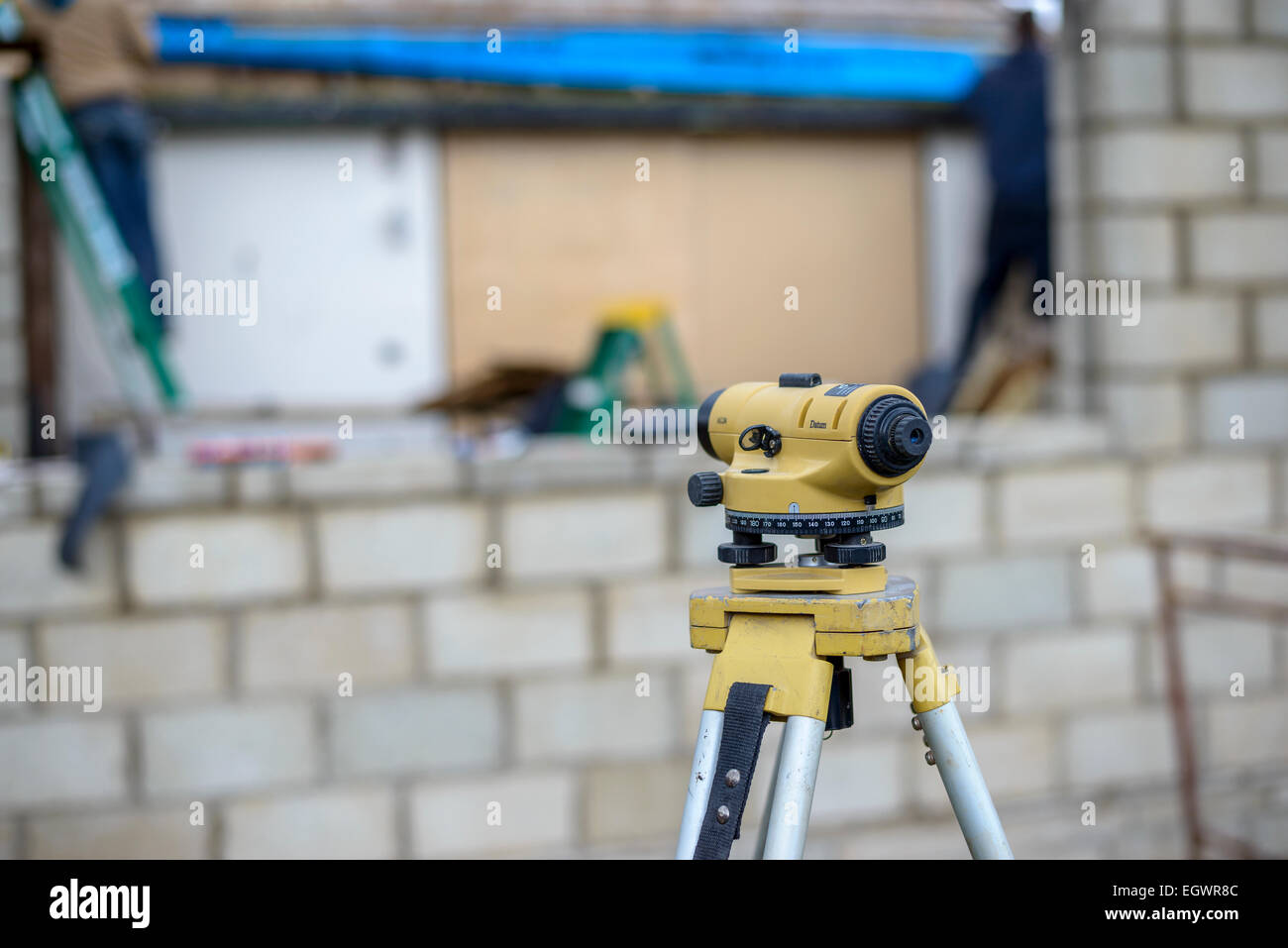 Grey grau Besser Betonklotz Breezeblock CMU konkrete Einheit Mauerwerk hinter einem gelben Theodolit unscharf gestellt. Stockfoto