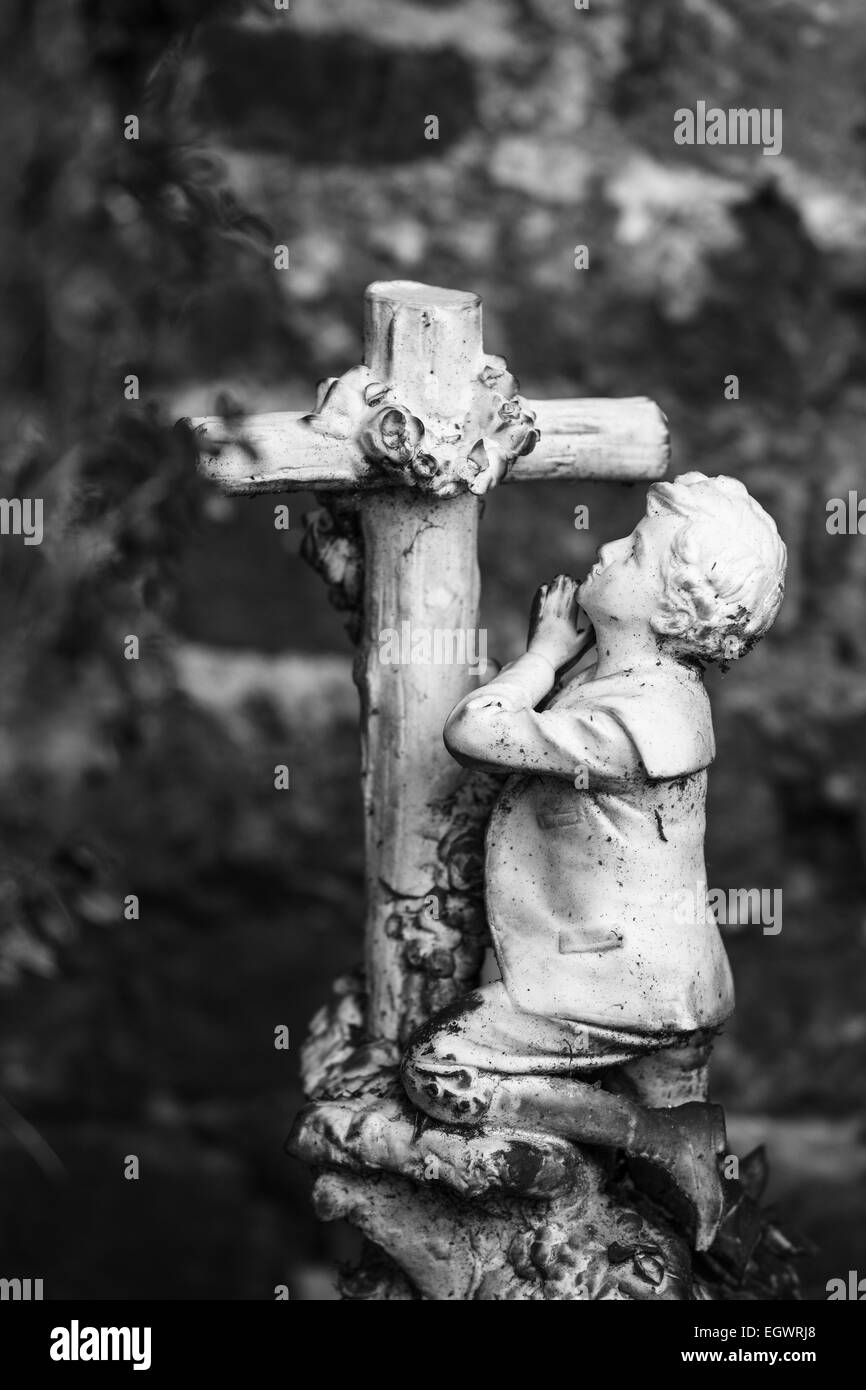 Friedhof-Statue, Praying Boy vor einem Kreuz Stockfoto