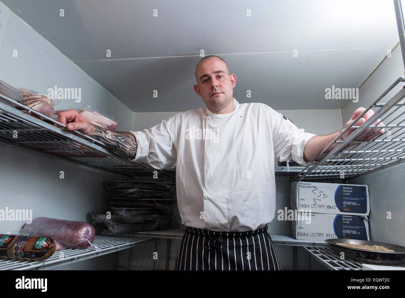 Eine professionelle bedeuten ^ launisch Koch steht in seiner Küche suchen, auf der Suche genervt mit vielen Kochutensilien im Hintergrund Stockfoto