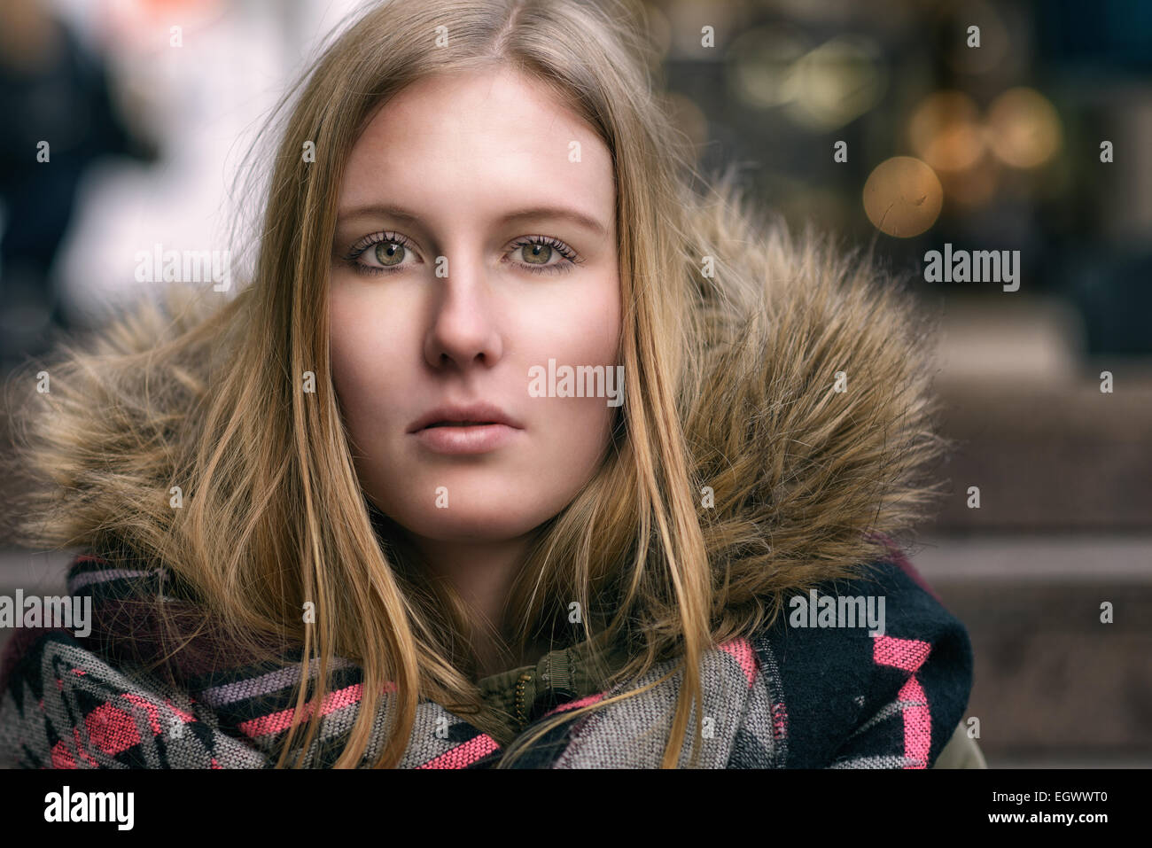 Attraktive ernste junge blonde Frau in einem warmen pelzige Winterjacke direkt in die Kamera schaut gekleidet Nahaufnahme Kopf und sho Stockfoto