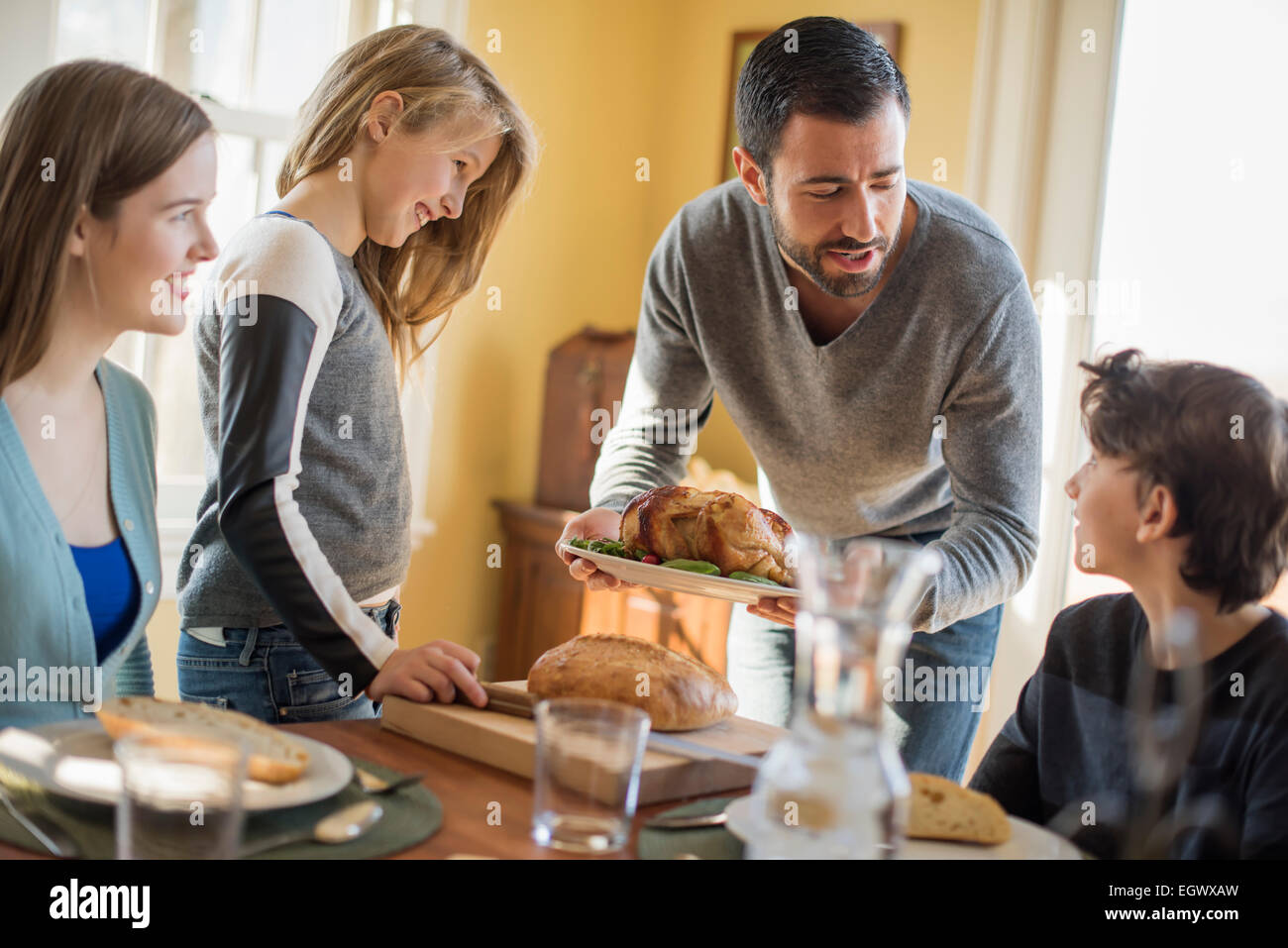 Erwachsene und Kinder versammelten sich um einen Tisch für eine Mahlzeit. Stockfoto