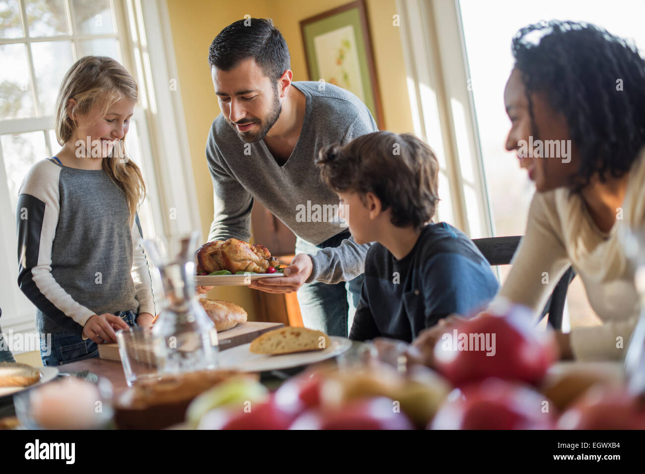 Erwachsene und Kinder versammelten sich um einen Tisch für eine Mahlzeit. Stockfoto