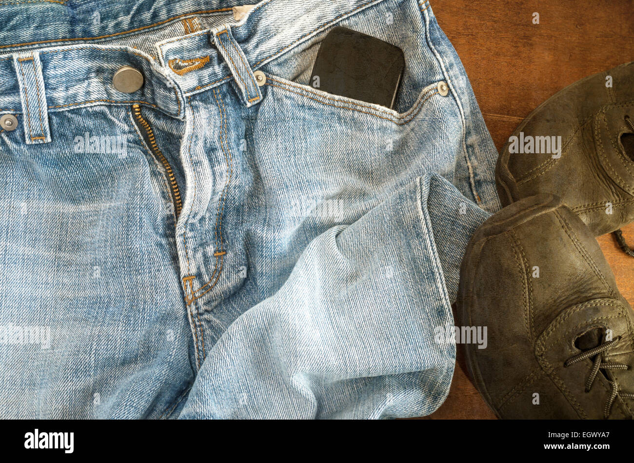 Detail der Blue Jeans mit schwarzen Schuhen auf hölzernen Hintergrund mit Grunge Texturen überlagert. Stockfoto