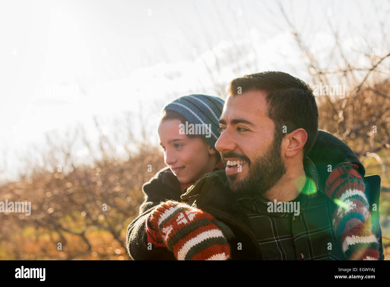 Ein Mann mit einem Kind Piggback auf seinem Rücken reiten. Stockfoto