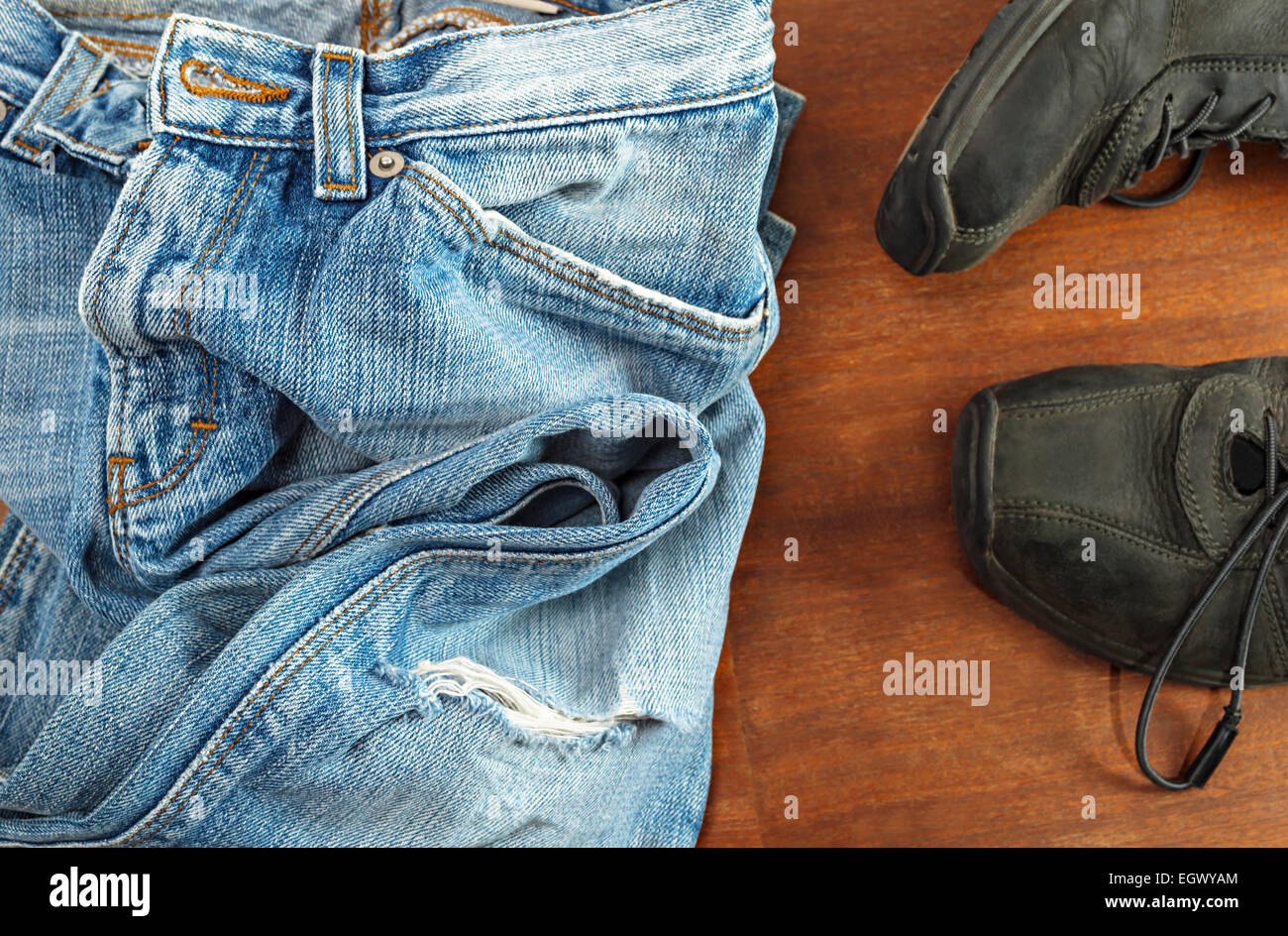 Detail der Blue Jeans mit schwarzen Schuhen auf hölzernen Hintergrund Stockfoto