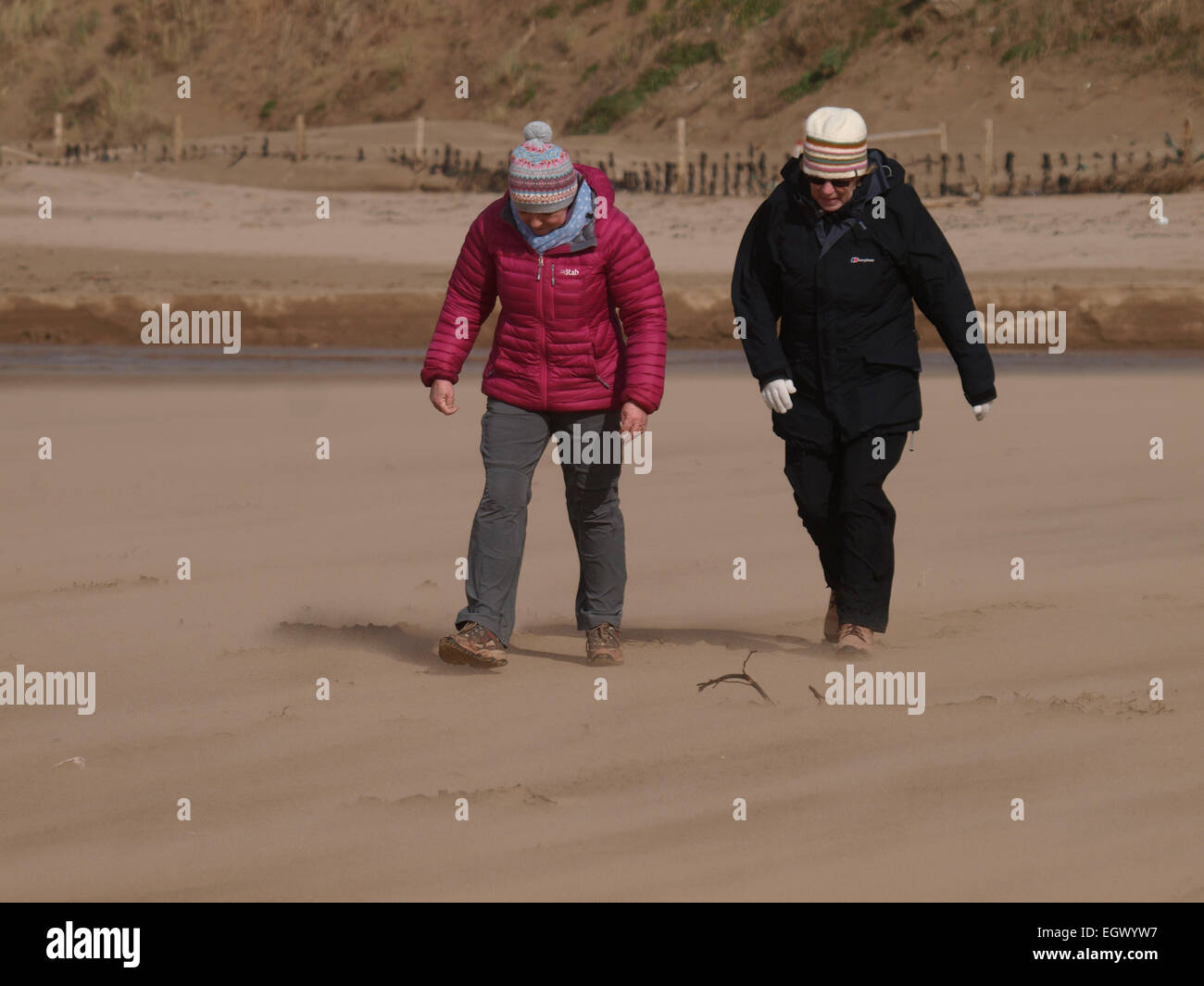 Zwei Frauen, die kämpfen, um zu Fuß in den Wind an einem sehr windigen Strand, Woolacombe, Devon, UK Stockfoto