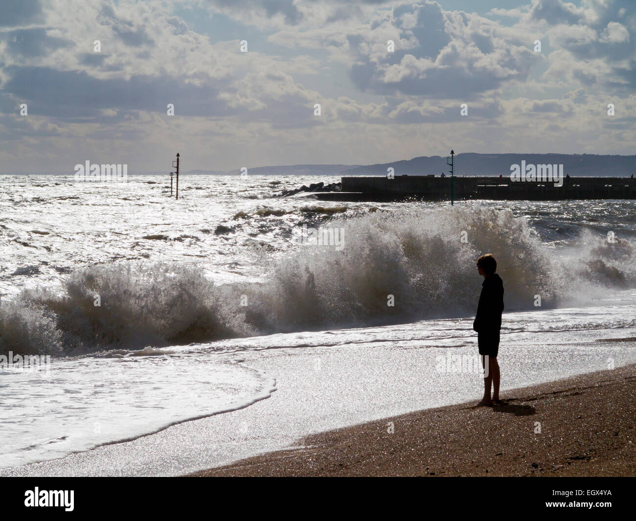 Teenager stehen Silhouette an einem Strand, Blick auf das Meer mit Wellen auf den Strand Stockfoto