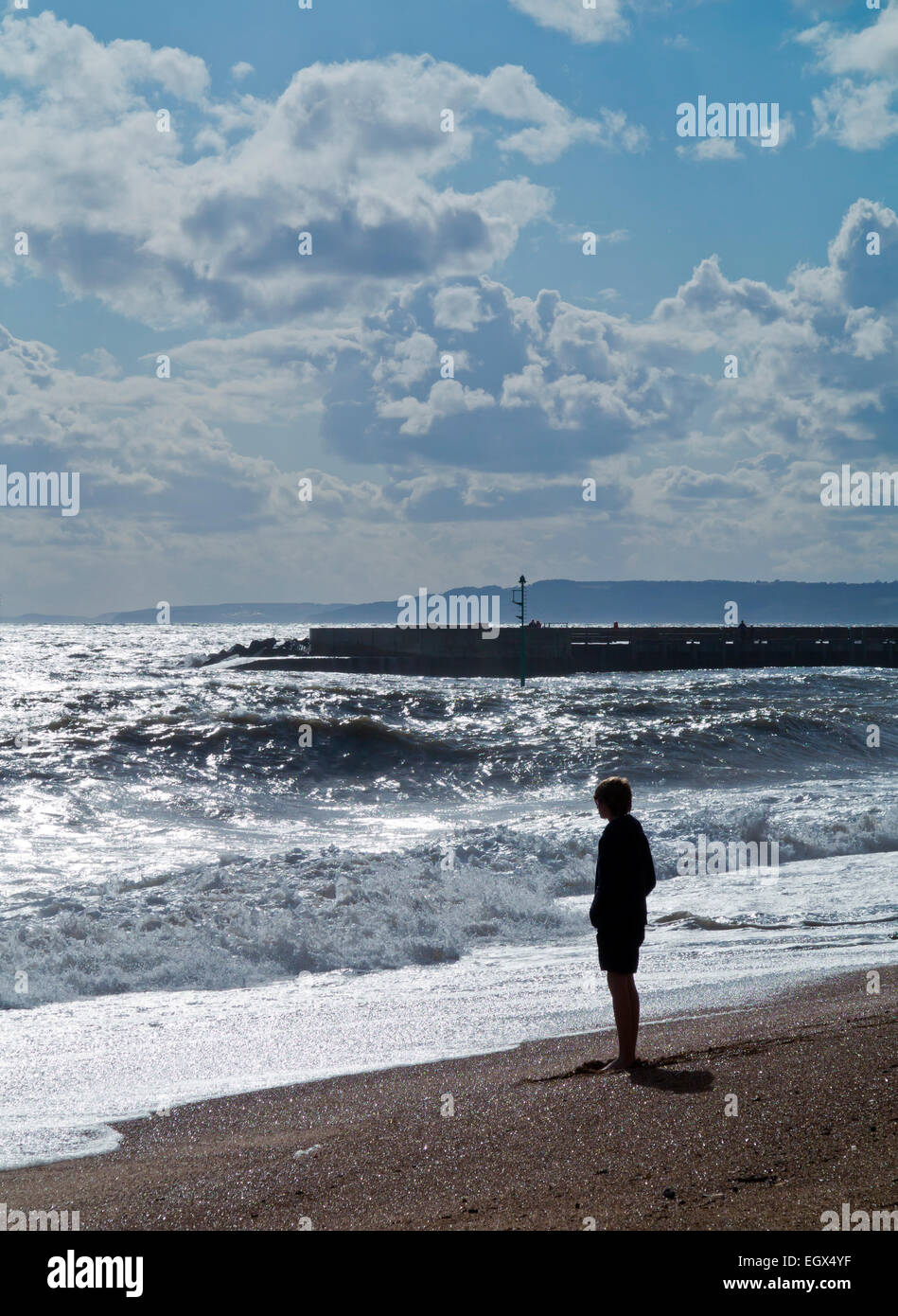 Teenager stehen Silhouette an einem Strand, Blick auf das Meer mit Wellen auf den Strand Stockfoto