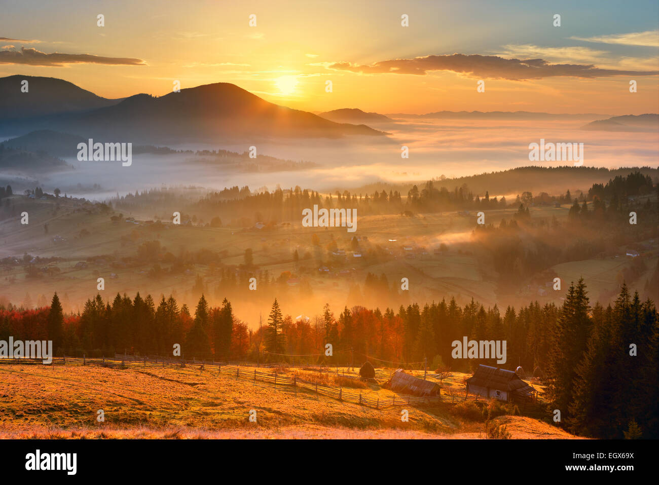 Sonnenaufgang, Bergdorf im Nebel und alles schön in gelbes Licht Stockfoto