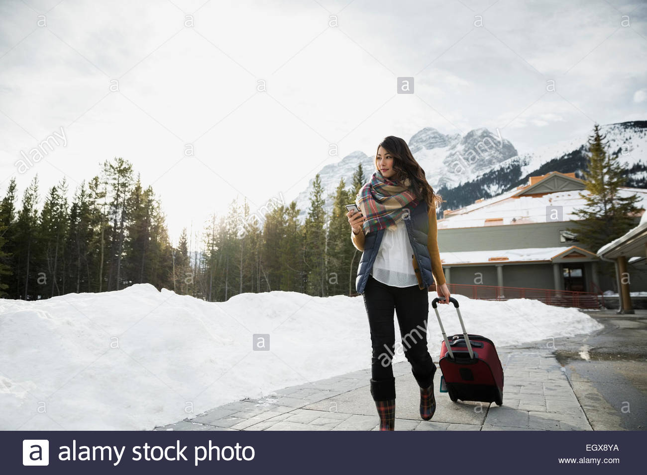Frau ziehen Koffer am Bürgersteig unter Bergen Stockfoto