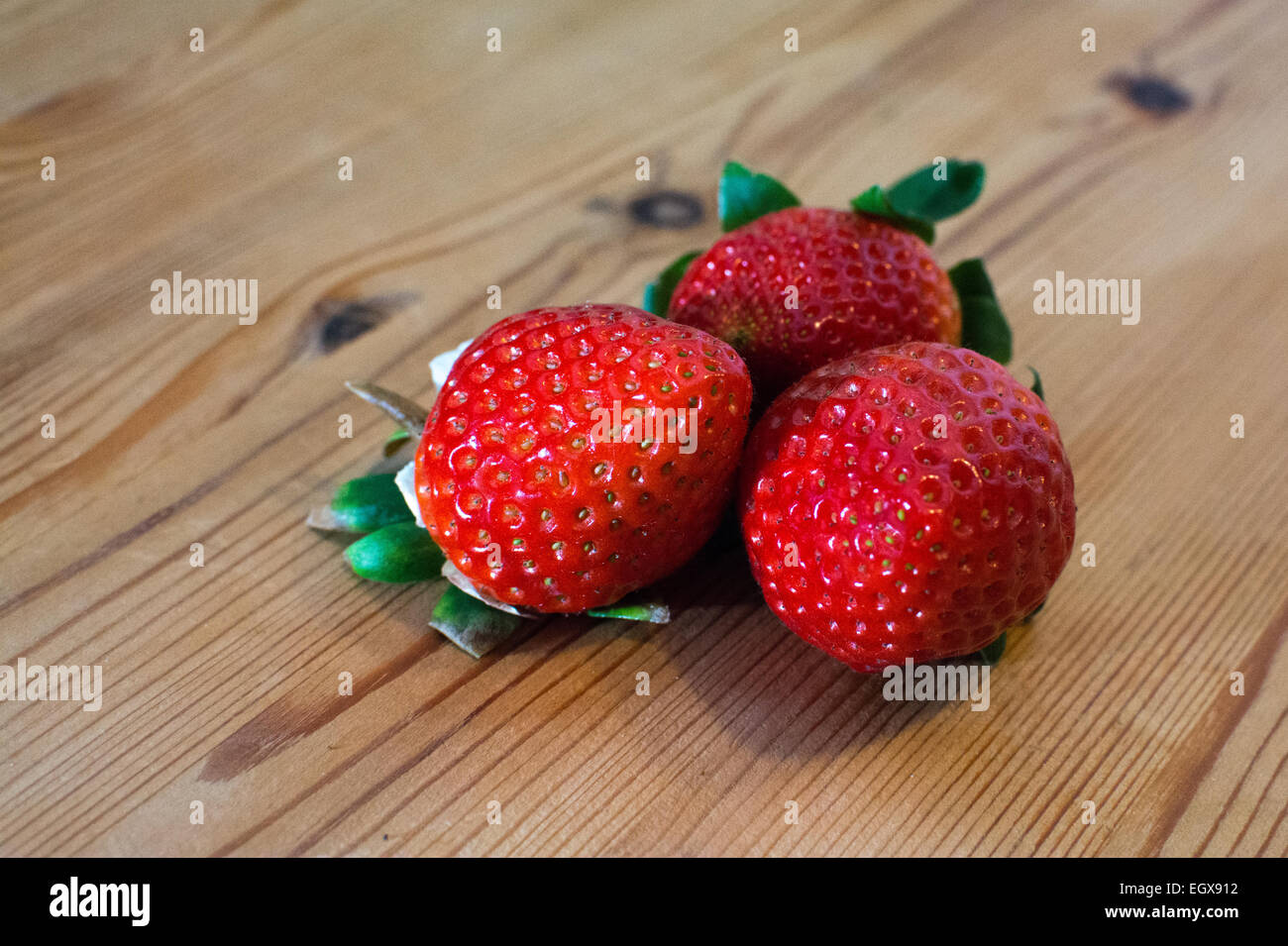 3 Erdbeeren auf einem Holztisch liegend Stockfoto