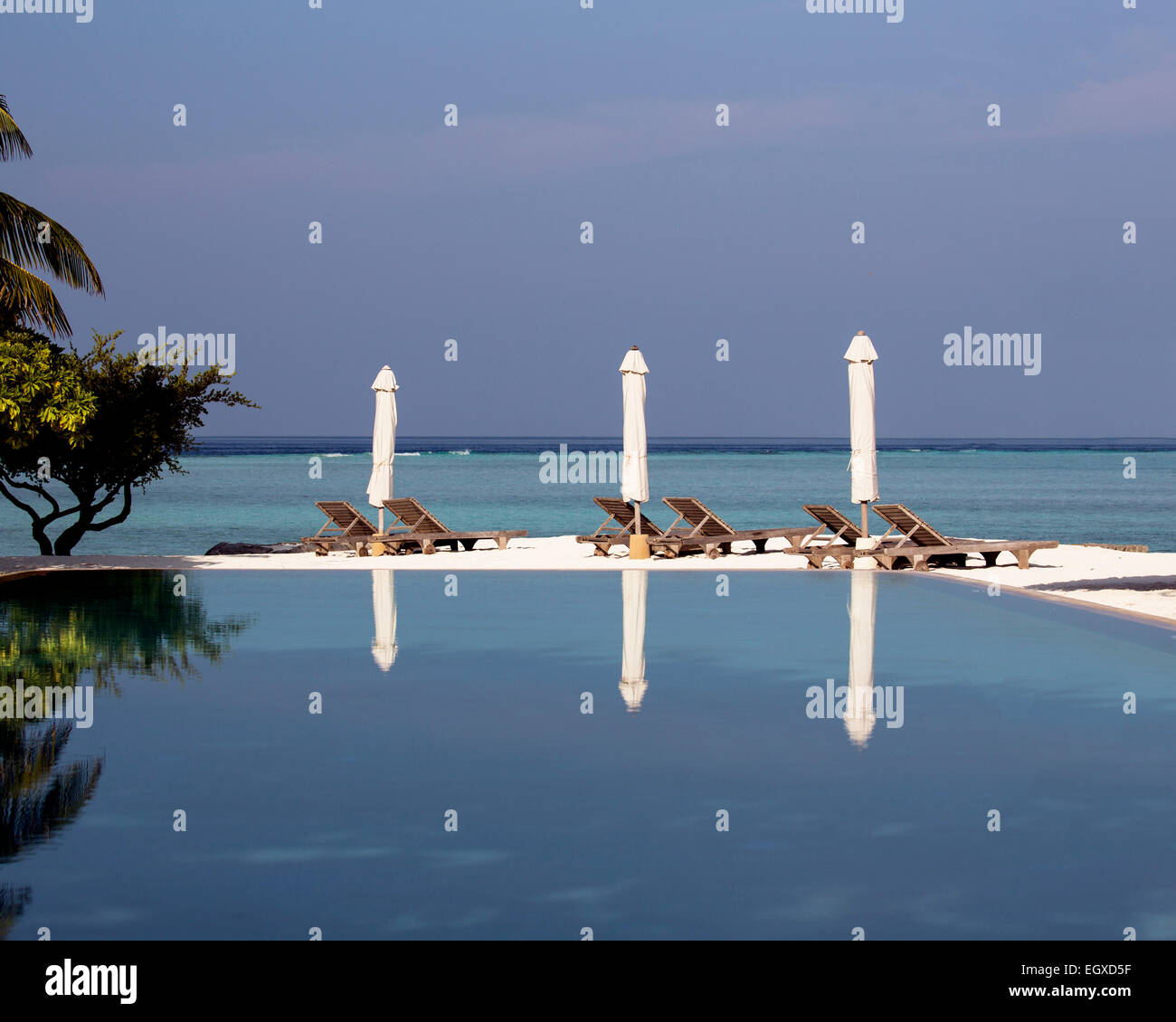 Drei gefalteten Sonnenschirme spiegelt sich in der Schwimmbad-Kunst ein Luxus resort auf den Malediven Stockfoto
