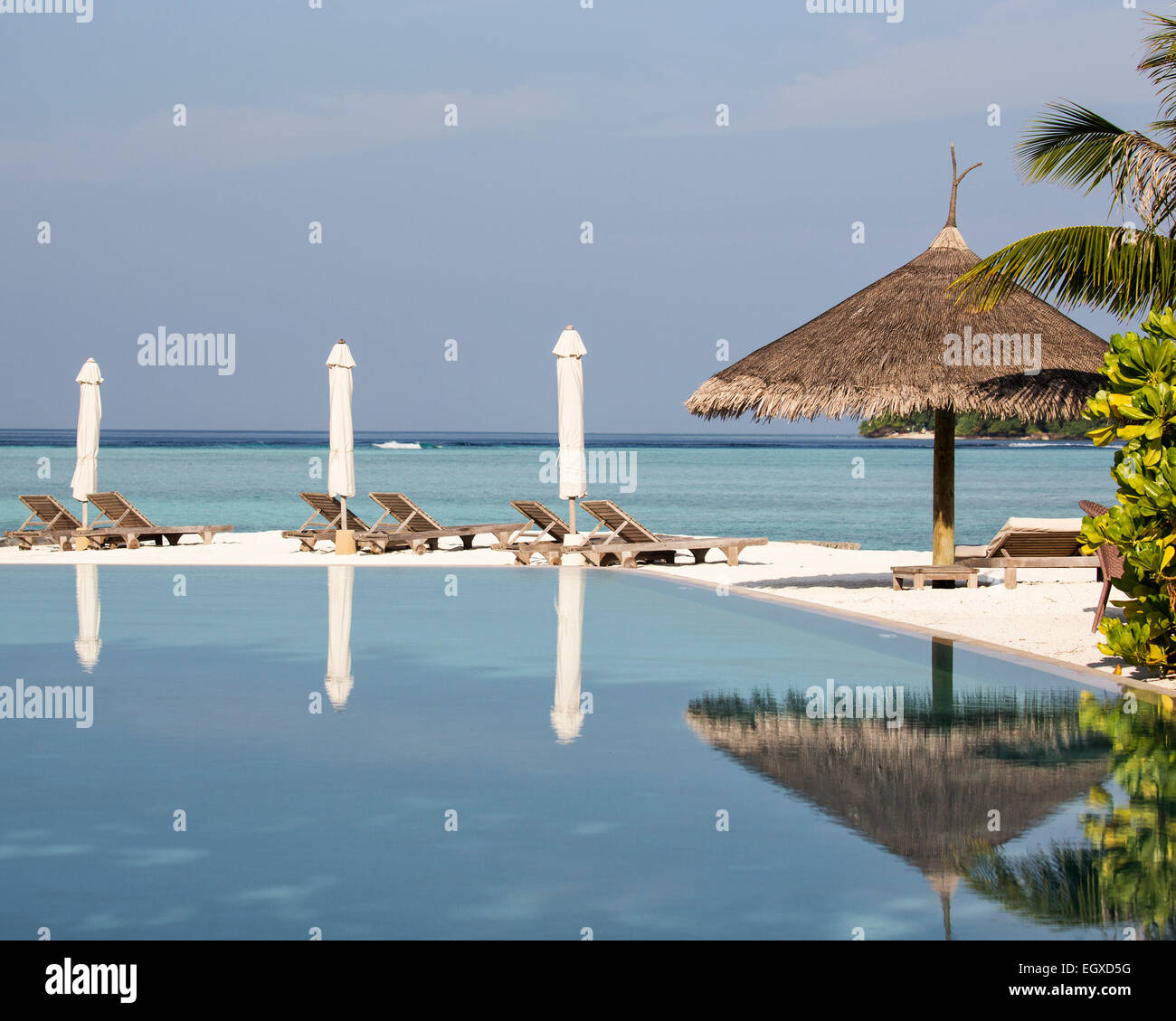 Drei gefalteten Sonnenschirme spiegelt sich in der Schwimmbad-Kunst ein Luxus resort auf den Malediven Stockfoto