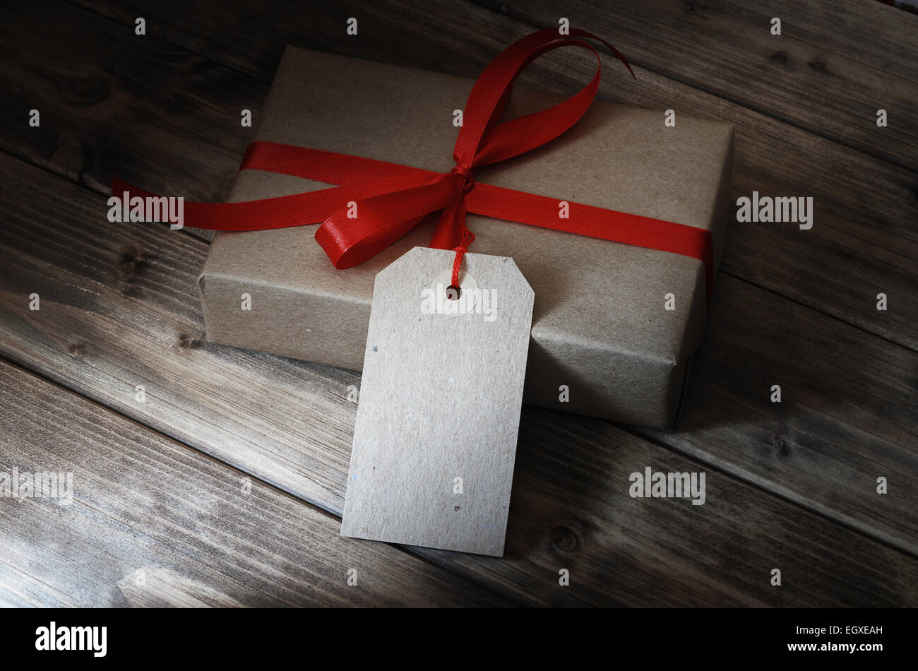 Geschenk-Box mit rotem Band und mit einem Preisschild auf Holztisch Stockfoto