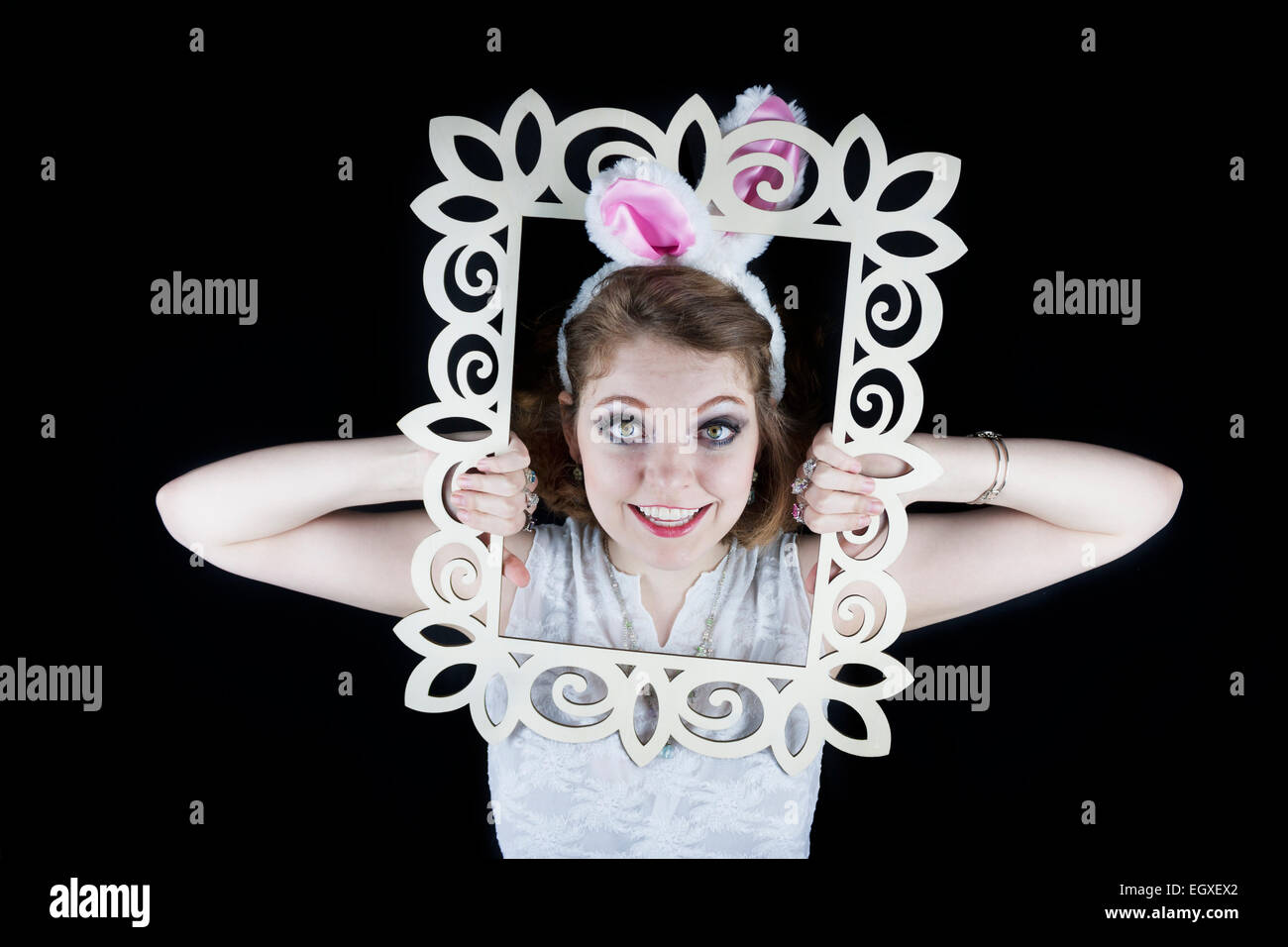 Junge Frau posiert mit Hasenohren und weißen Rahmen auf schwarzem Hintergrund. Stockfoto