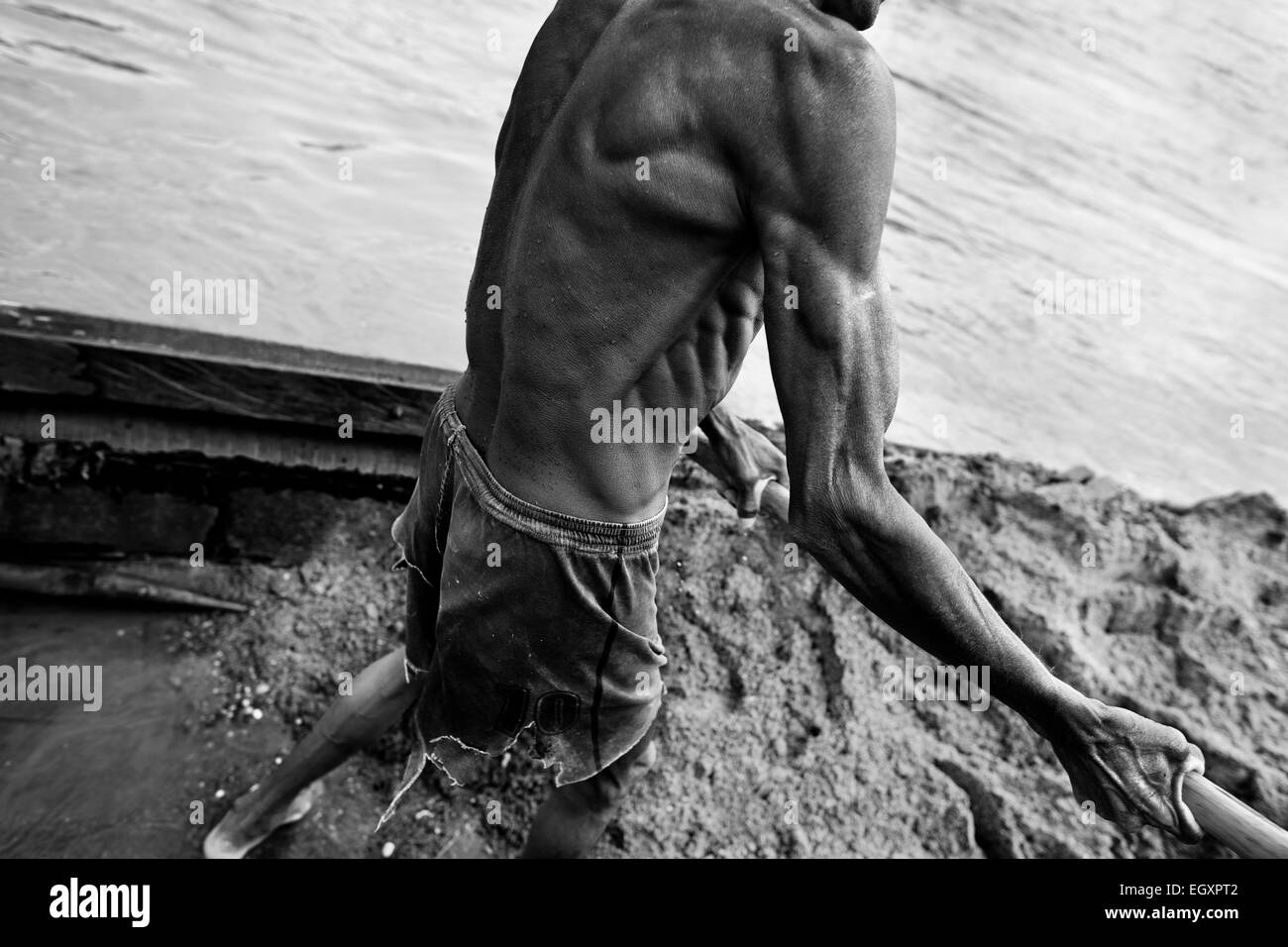 Ein kolumbianische Sand Bergmann entlädt den extrahierten Sand aus seinem Boot am Ufer des Flusses La Vieja in Cartago, Kolumbien. Stockfoto