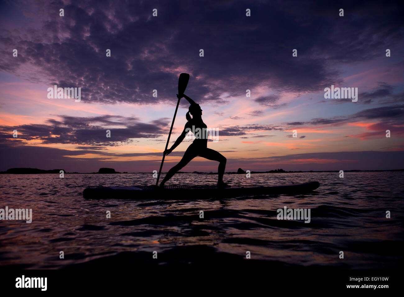 Eine junge Frau erstreckt sich auf einem Surfbrett während einer Yoga-Lektion Stockfoto