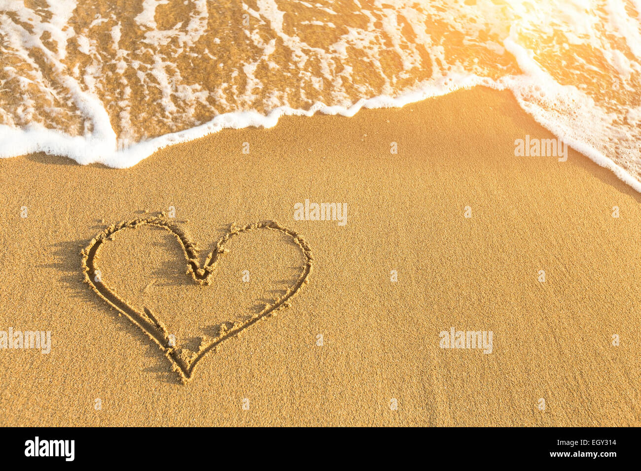 Herz in Meer Strandsand, weiche Welle an einem sonnigen Sommertag gezeichnet. Stockfoto