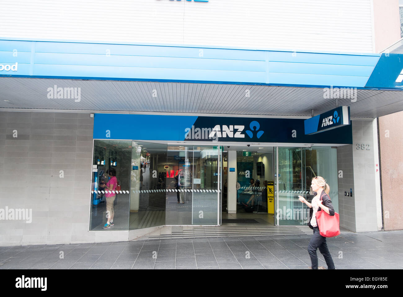 Dame, die an ANZ Australia und New Zealand Bank Filiale in Chatswood Sydney, NSW, Australien vorbeiläuft Stockfoto