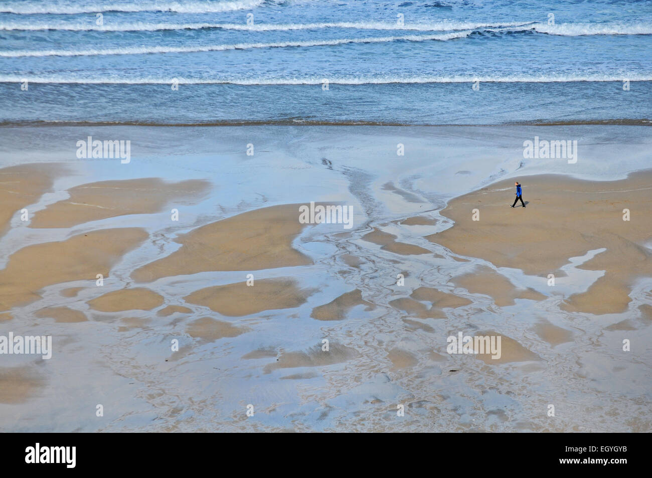 Ein Mann geht an einem Strand in Newquay, Cornwall Stockfoto