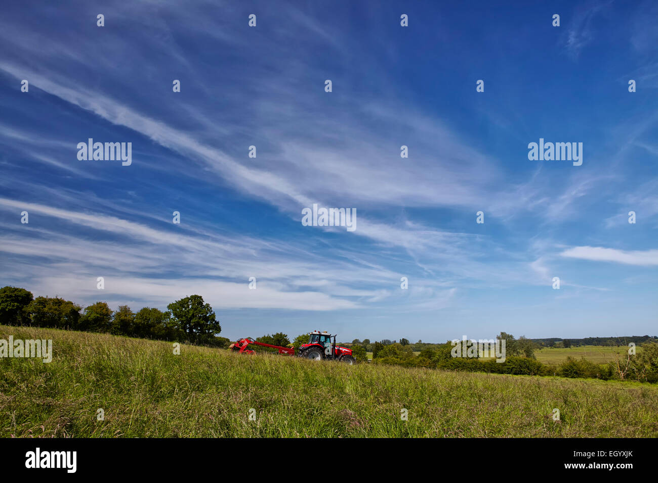 Traktor und Mähwerk arbeiten in der englischen Landschaft Stockfoto