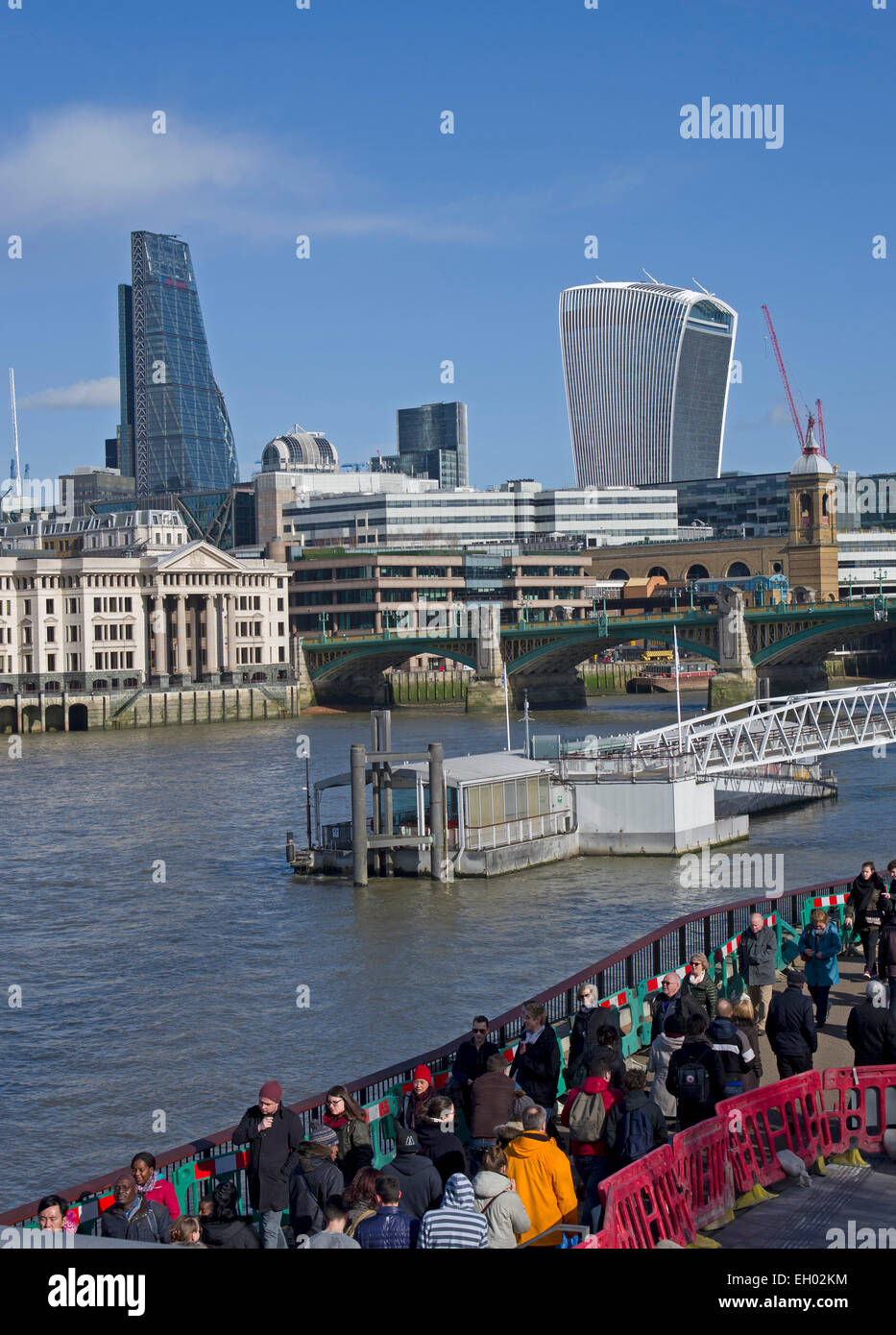 Besucher drängen sich die Wege von South Bank. Blick auf die neuesten Gebäude der City of London von der Millennium Bridge Stockfoto