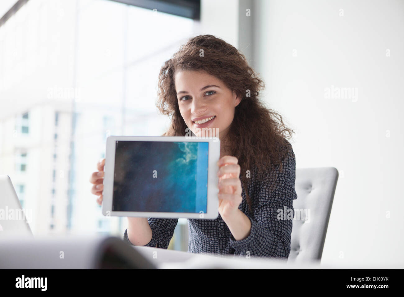 Porträt der lächelnde junge Frau am Schreibtisch hält digital-Tablette Stockfoto
