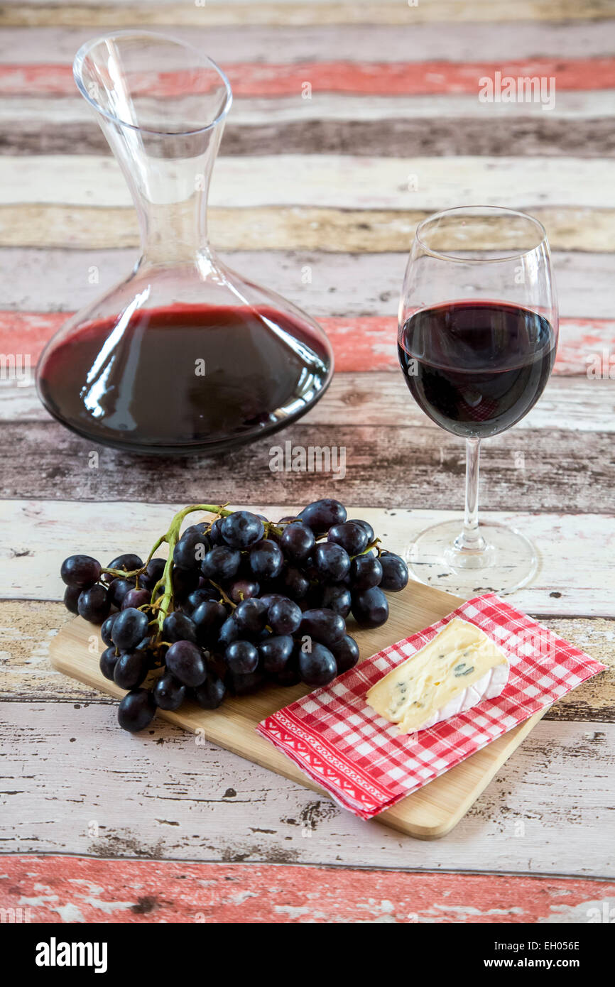 Blaue Trauben, Käse, Dekanter und Glas Rotwein Stockfoto