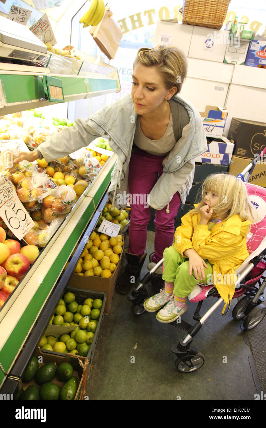 Mutter mit Kleinkind im Kinderwagen Auswahl Gemüse & Obst - Modell veröffentlicht Stockfoto