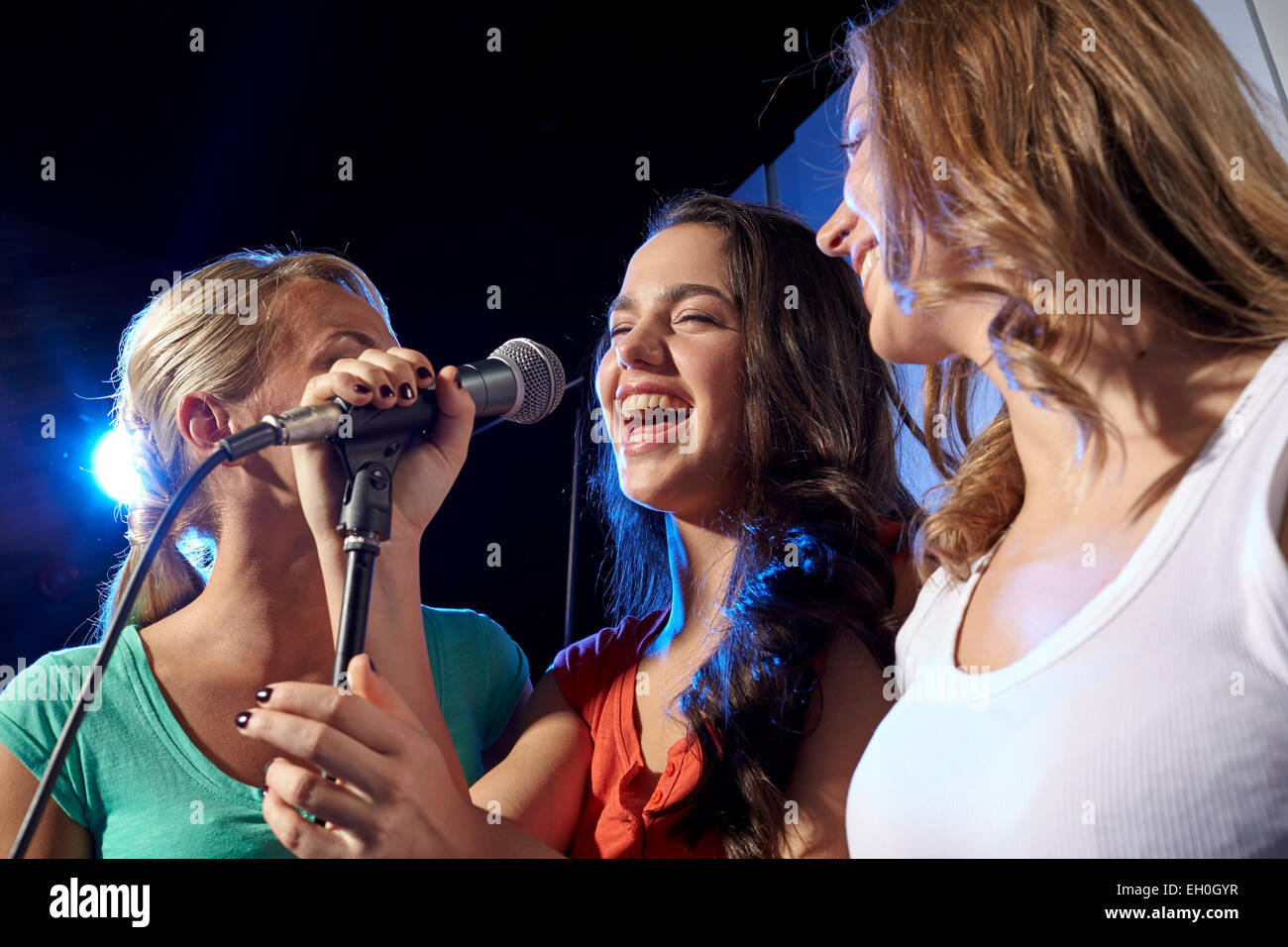 glückliche junge Frauen singen Karaoke im Nachtclub Stockfoto