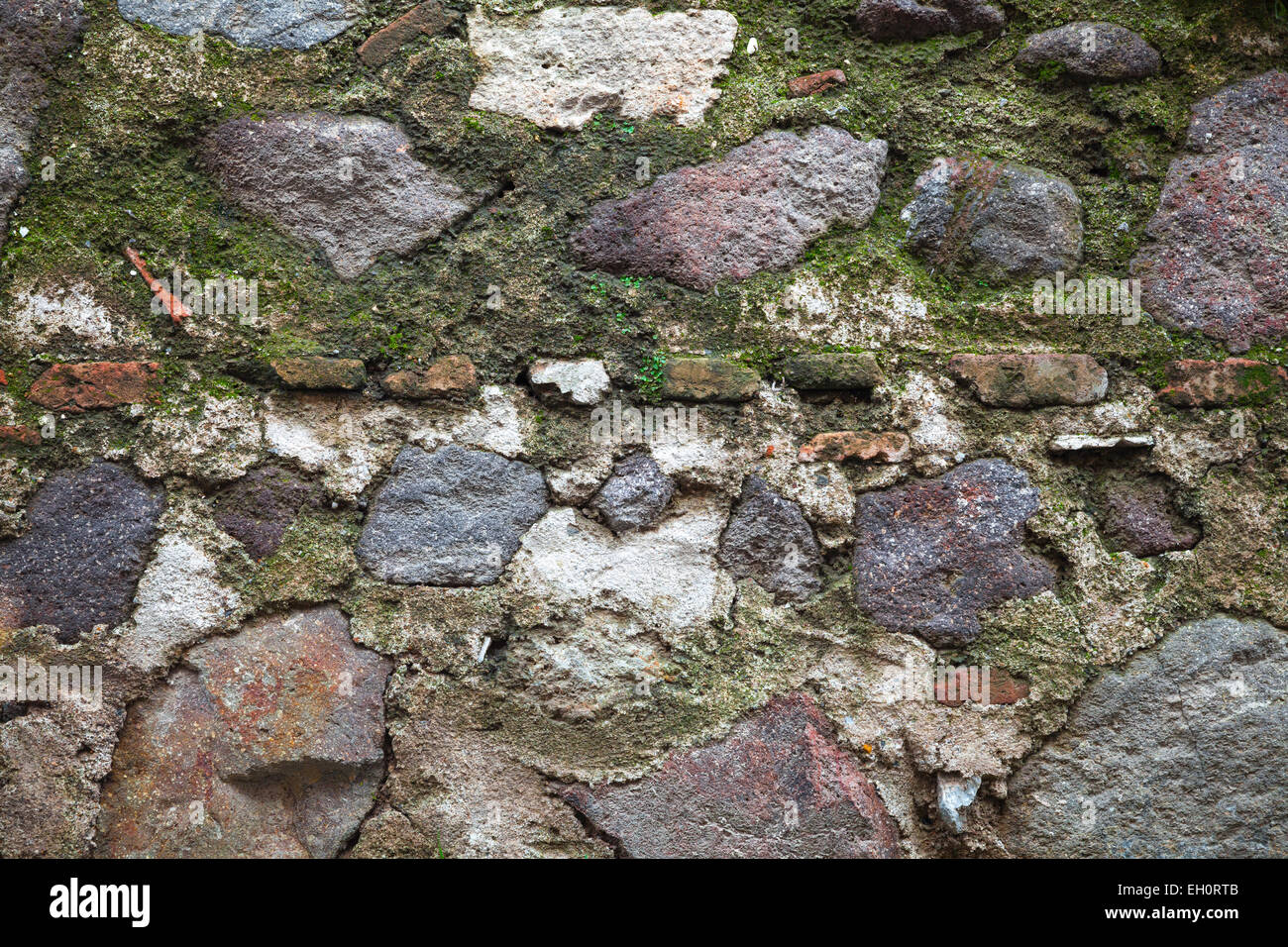 Alten Festungsmauer von dunklen grauen Steinen mit grünem Moos, detaillierte Hintergrundtextur gemacht Stockfoto