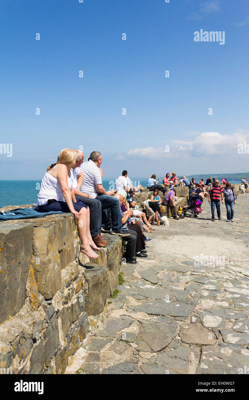 Besucher in New Quay, Ceredigion, genießen die Sommersonne auf dem steinernen Pier mit Blick auf Bucht New Quay. Stockfoto