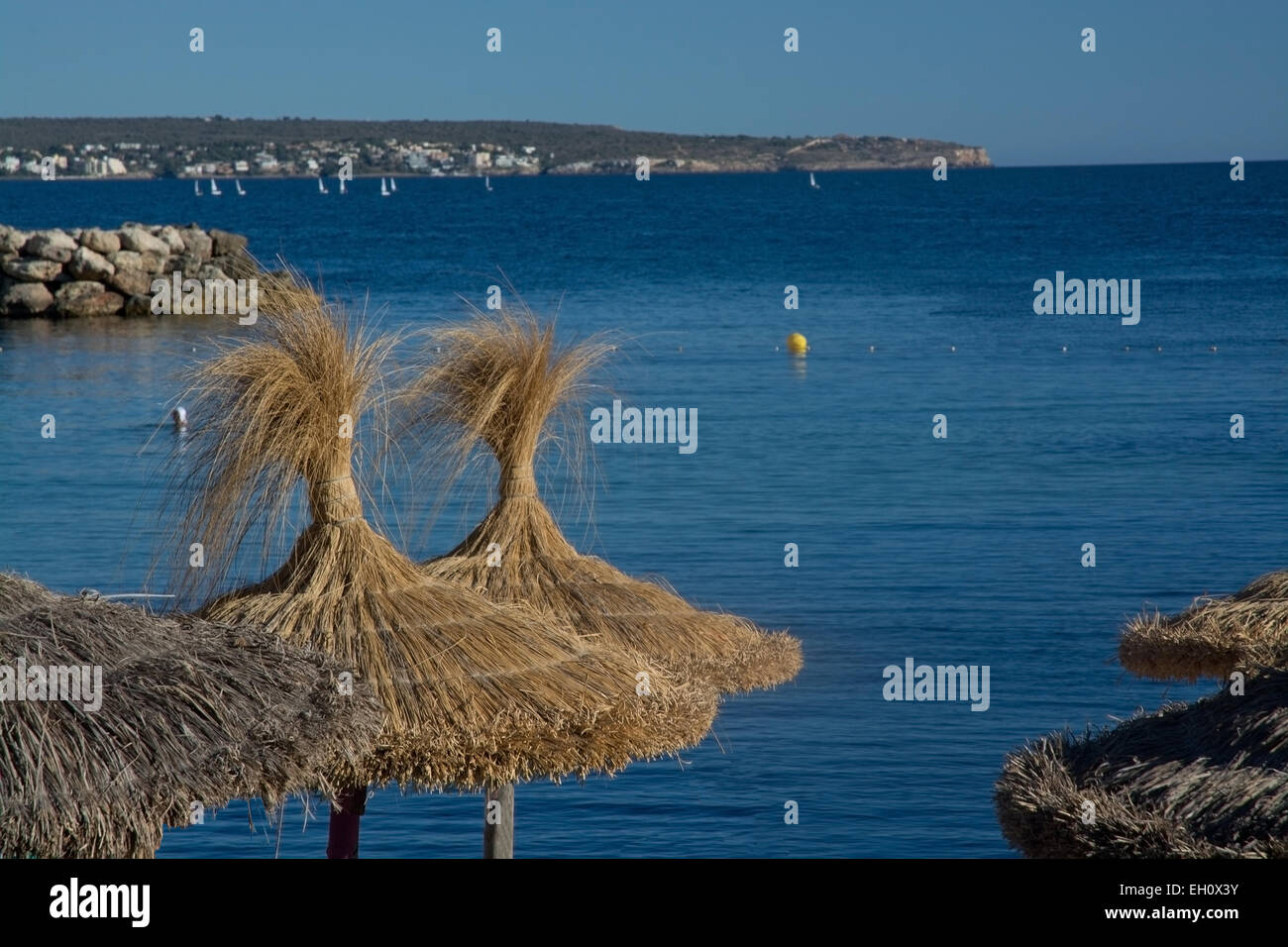 Blaues Meer und Stroh braun Sonnenschirme in Mallorca, Balearen, Spanien. Stockfoto